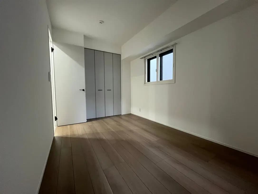 シンプルなデザインの空の部屋、木製フローリングとホワイトのクローゼットが特徴的なインテリア