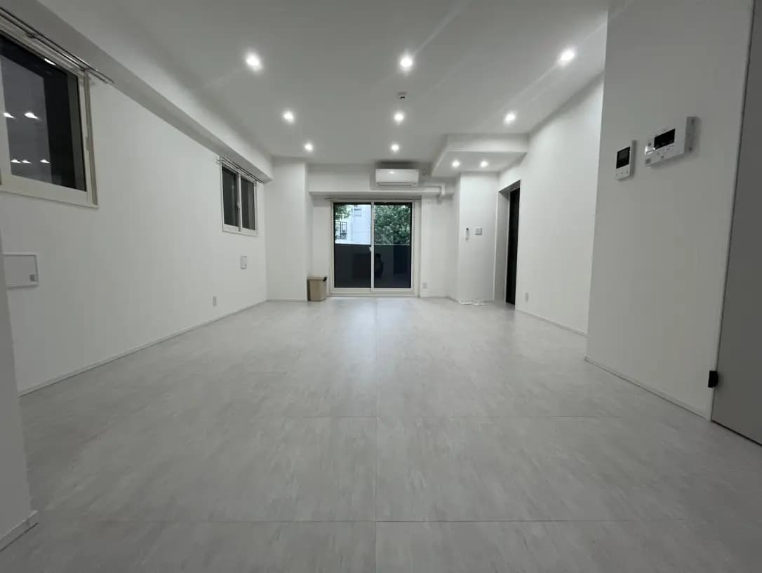 シンプルでモダンな新築住宅のリビングルーム、床はホワイト系のタイル、LEDダウンライト、大きな掃き出し窓とガラス扉で自然光が差し込む明るい空間