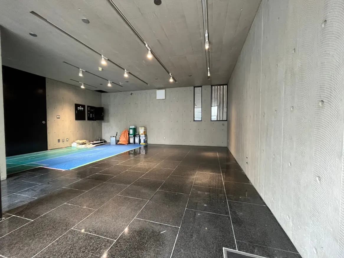 モダンな空間デザインの公共施設のロビー、コンクリート壁と黒いタイルのフロア、窓からの自然光