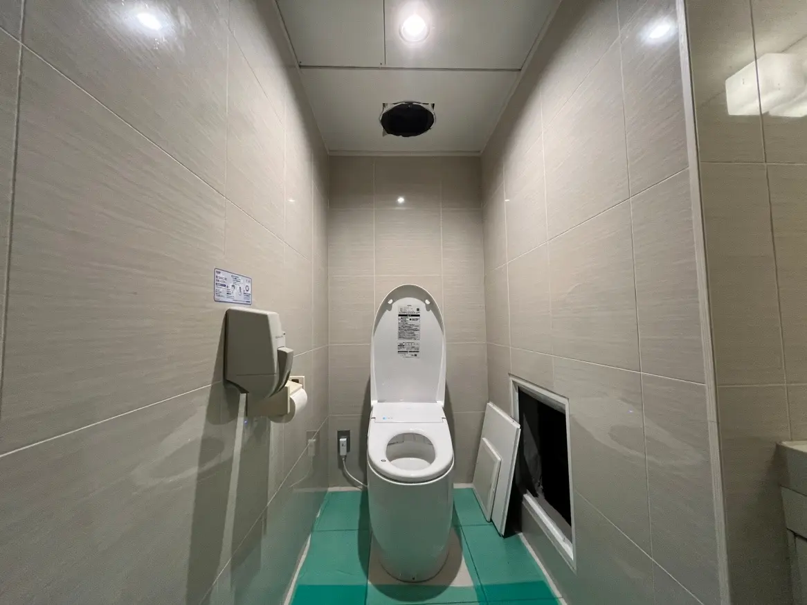 清潔でモダンなトイレの内装、壁はライトベージュのタイル、明るいLED照明