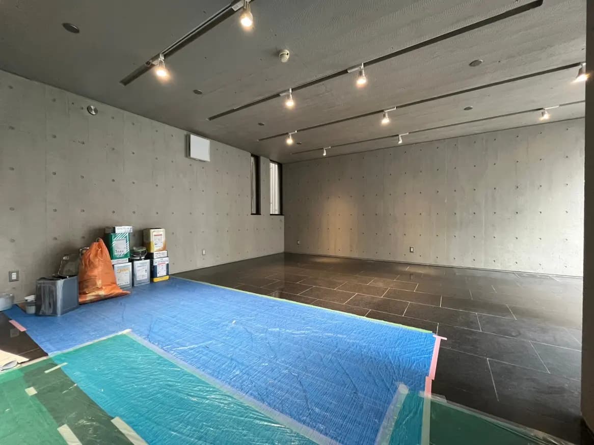 コンクリート打ち放しの壁と天井、スポットライトが取り付けられたモダンな内装の空間