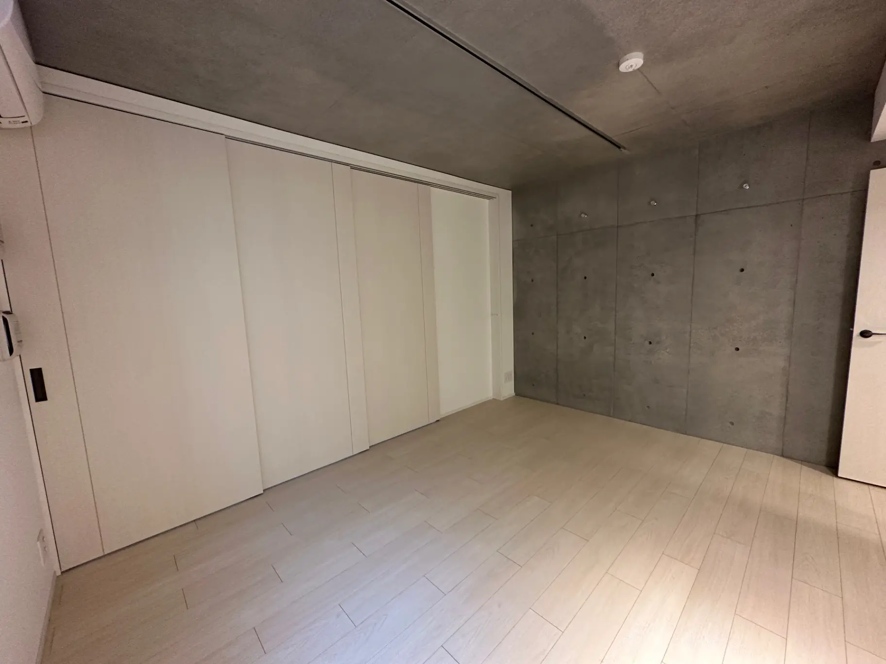 モダンな設計の広々とした空の部屋、白いクローゼットとコンクリートの壁
