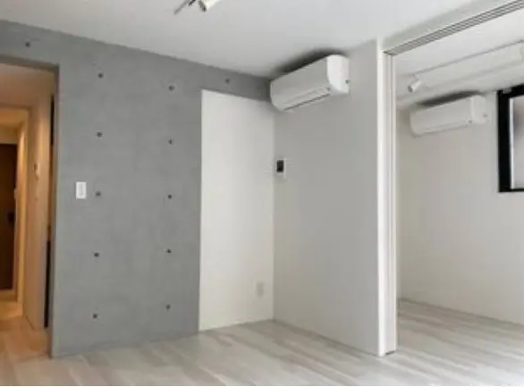 シンプルなモダンな空間デザインの部屋、グレーのアクセントウォール、エアコンと木目調フローリングが特徴のインテリア
