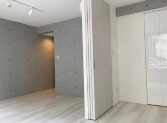 シンプルなデザインの明るい空間、グレーの壁と白木目調のフローリングが特徴の部屋