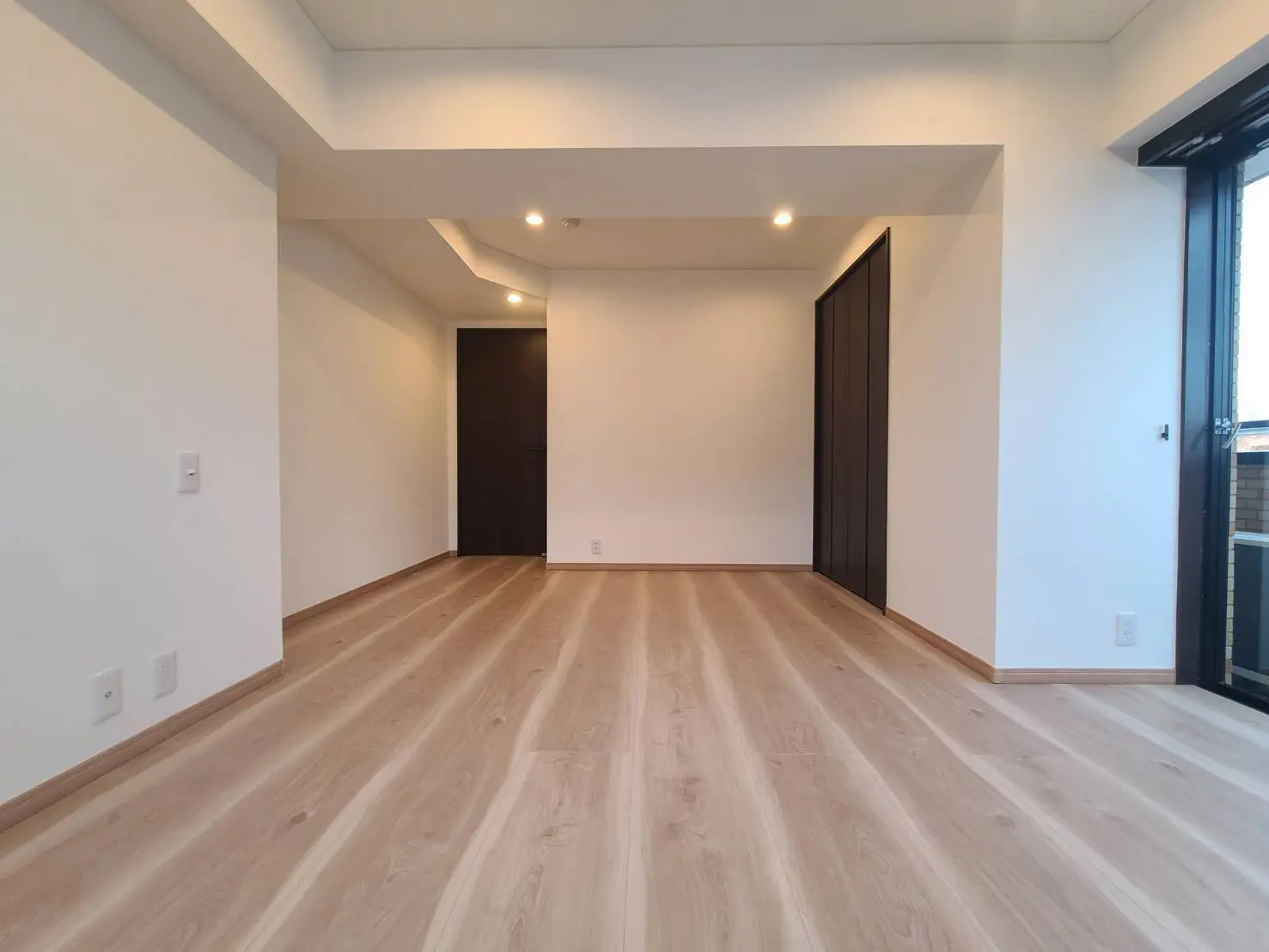 明るい照明と木製フローリングの新築マンションの空いている部屋、ガラスドアと内装デザイン