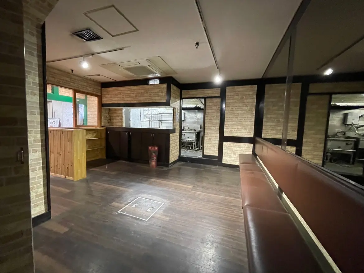 レンガ壁のレトロな内装のレストラン、木製の床とカウンター、ブース席がある空間