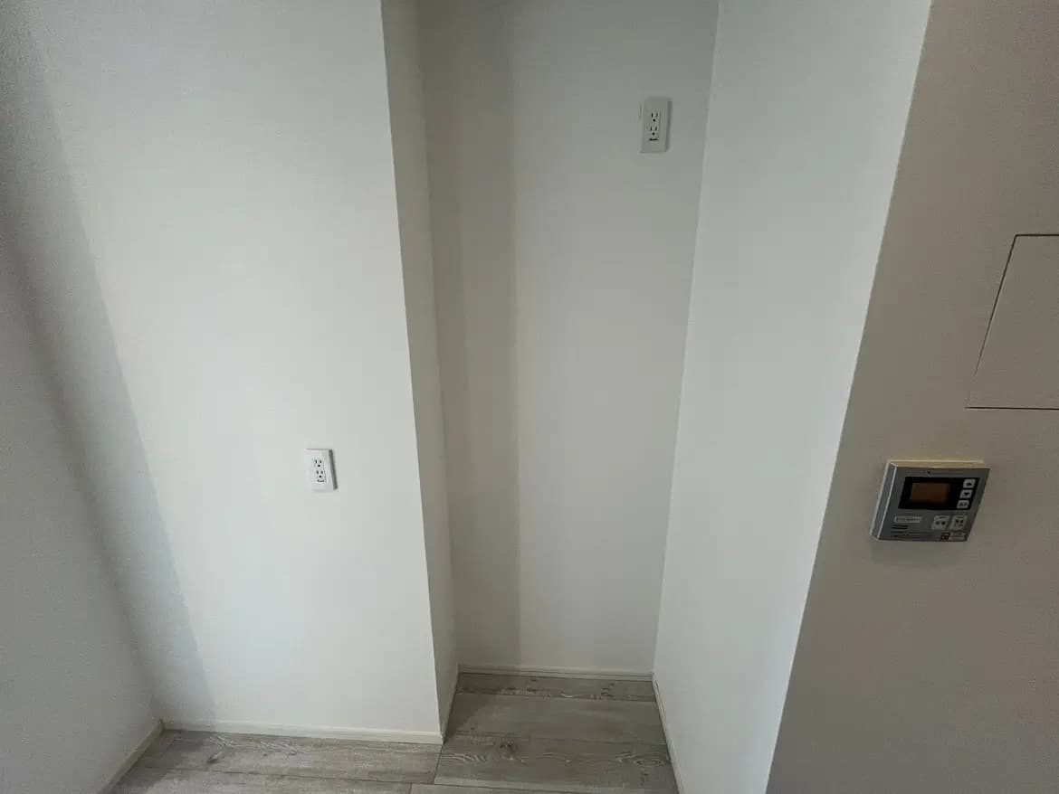 シンプルなインテリアの角部屋、壁にスイッチとセキュリティパネルが備え付けられているモダンな家の詳細