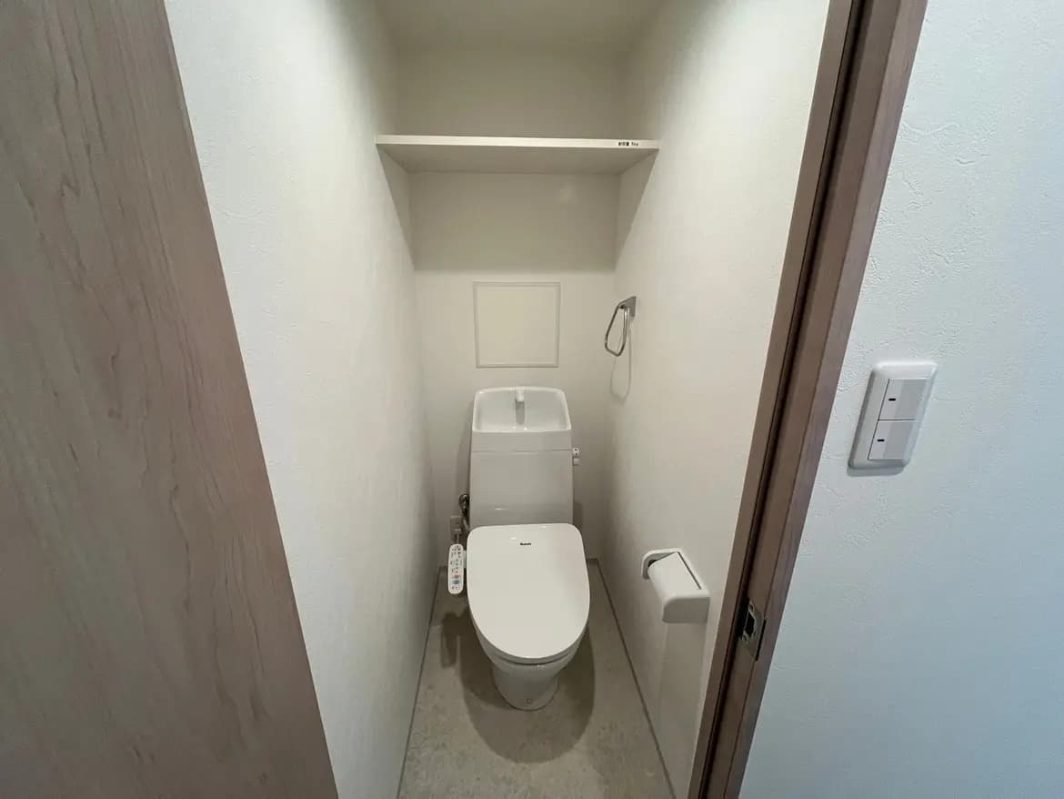 シンプルでモダンな洗面所、ウォシュレット付きトイレと白い壁、省スペース設計のインテリア