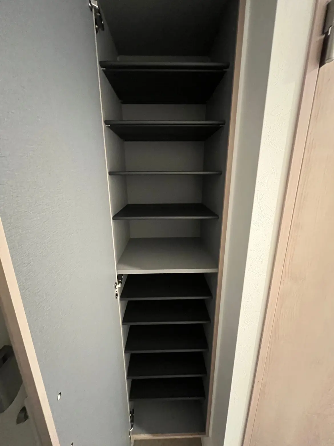 空の収納棚、グレーの壁に設置された黒い棚板が特徴的なモダンな家具