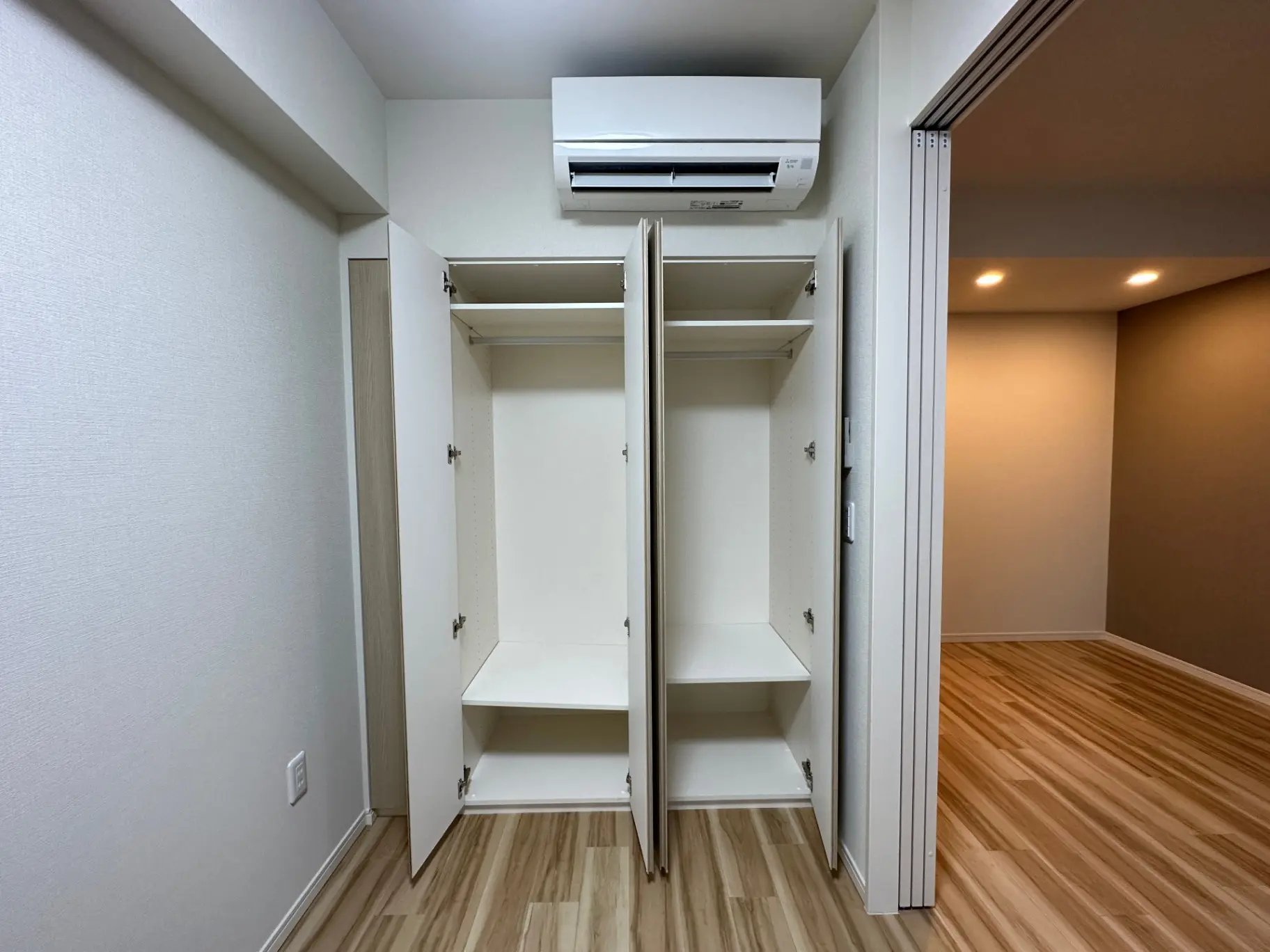 エアコン設備付きのクローゼットと木目フローリングのお部屋