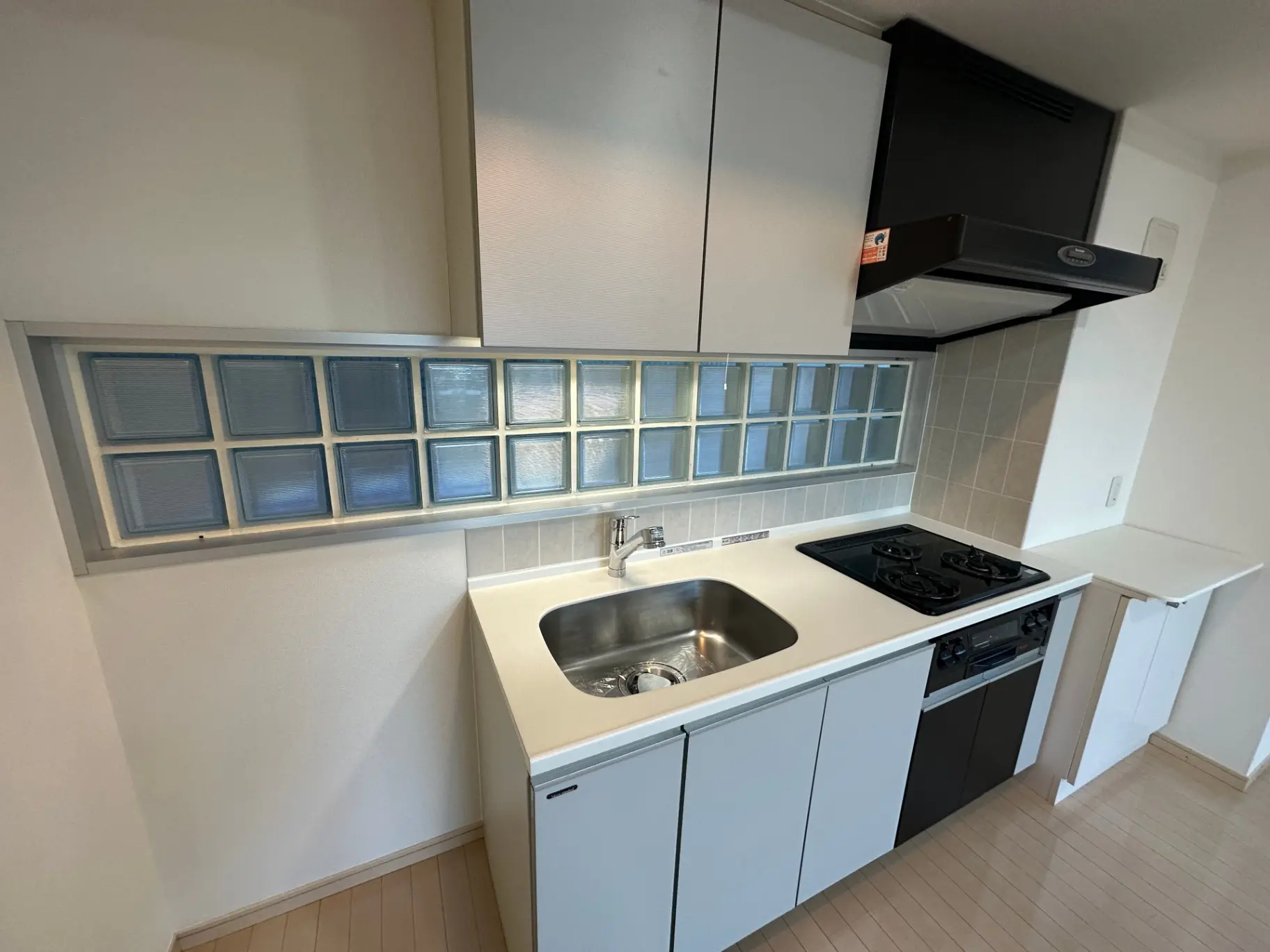 コンパクトなキッチンスペース、ブロックガラスの窓、四口ガスコンロ