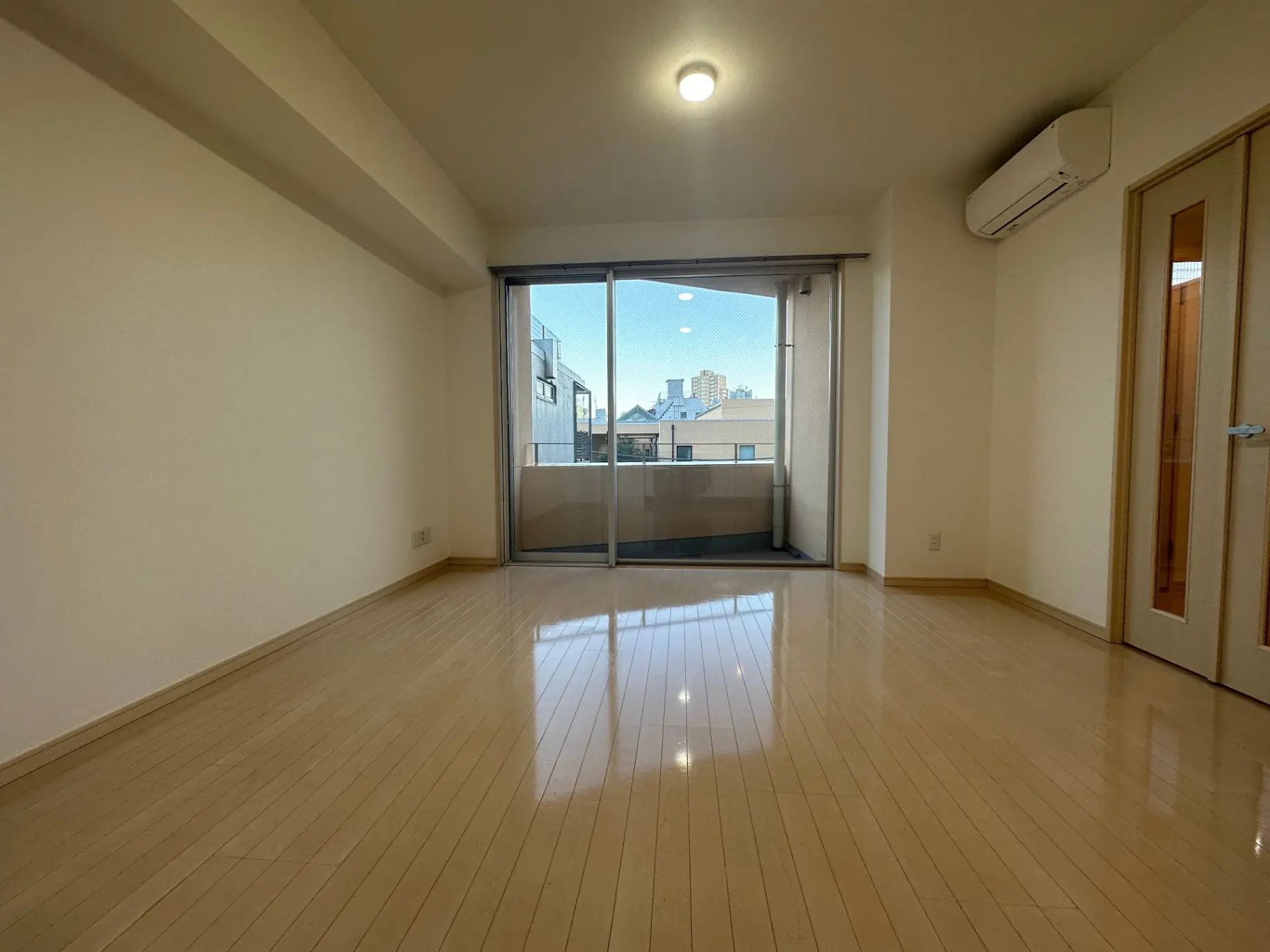 日差しが入る明るいリビングとガラス扉付きのバルコニー