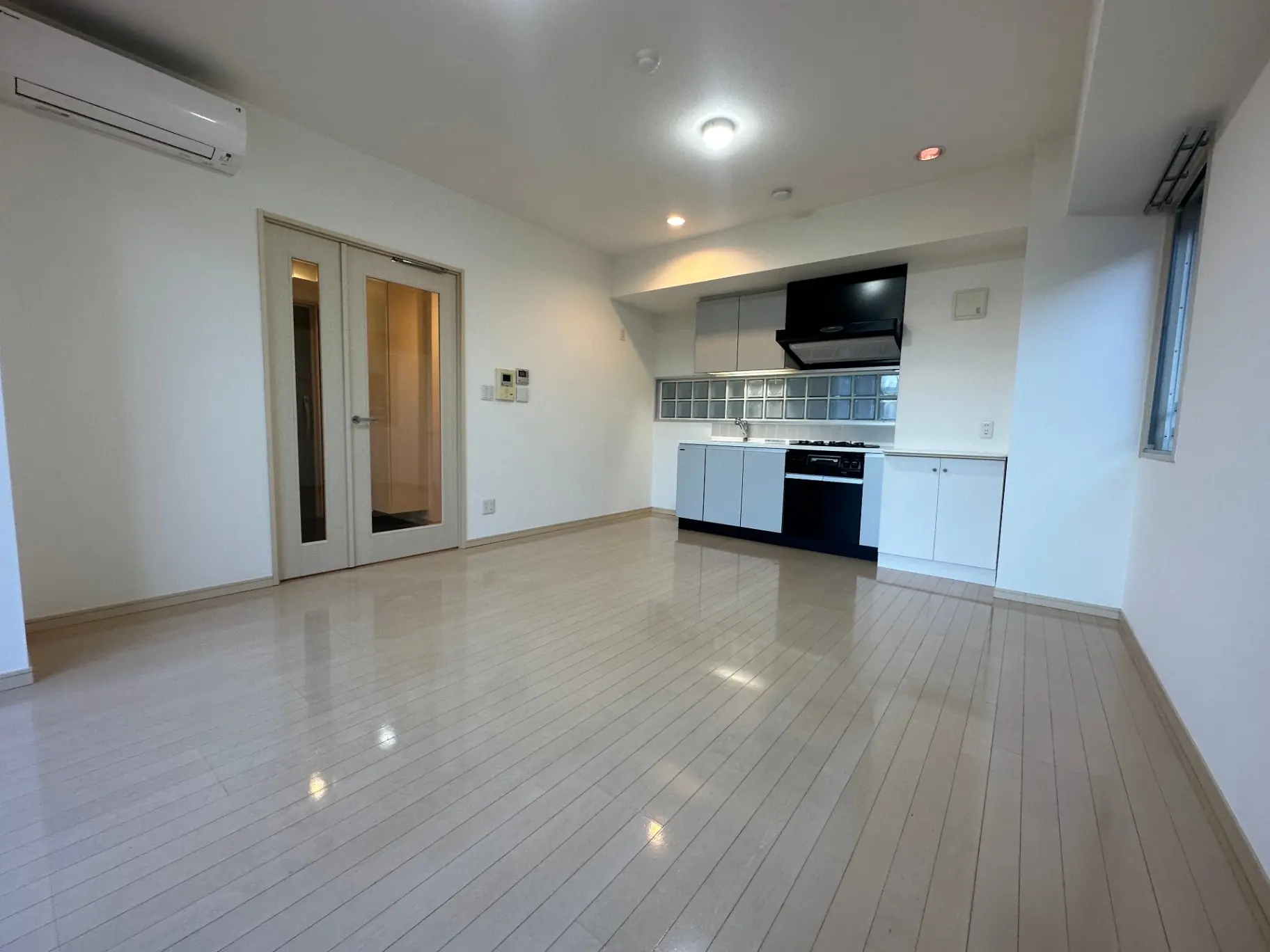 明るい室内照明と広々とした空間のリビング、三口コンロが付いた機能的なキッチン