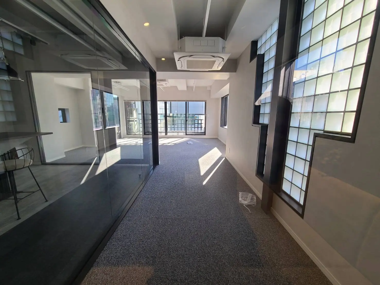 モダンなオフィス空間の内装、ガラスの間仕切り、和風の窓、日差しを浴びる清潔感のあるラウンジエリア