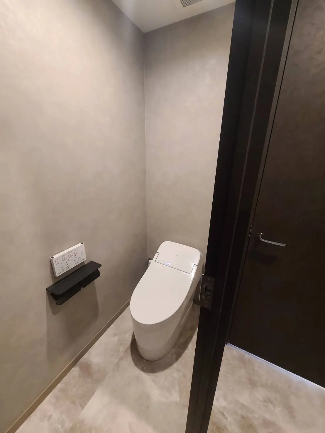 シンプルなデザインのトイレ、壁に取り付けられたトイレットペーパーホルダー、モダンなインテリア