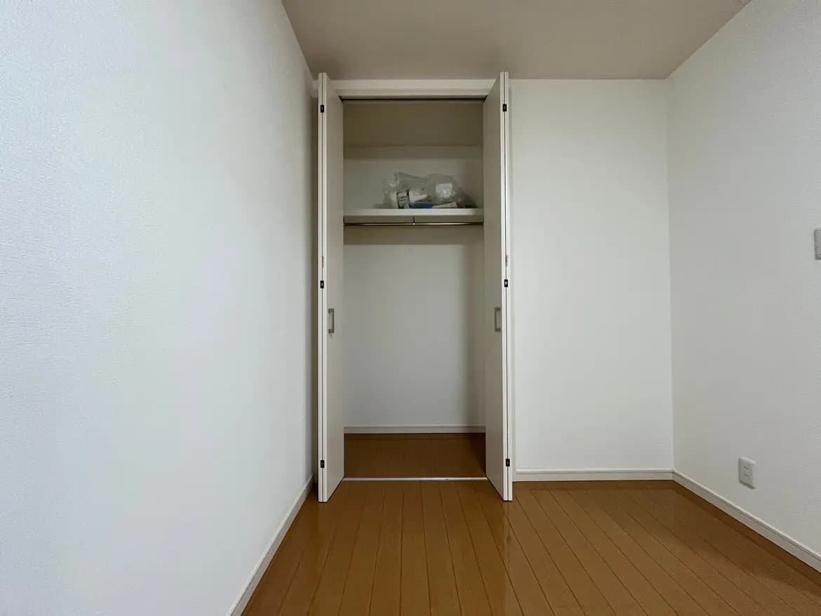 シンプルなデザインの空の部屋、木製フローリング、白い壁と開いたクローゼット