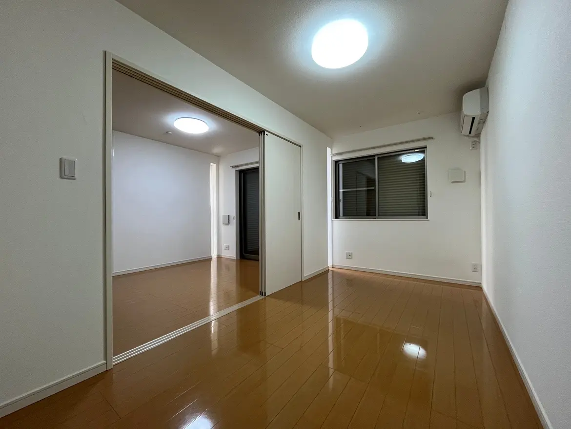 空間が広々とした現代的なリビングルーム、光沢のある木製フローリング、白い壁、クリーンなデザインの照明とエアコン付きインテリア