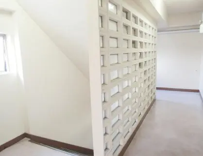 白い壁と独特な格子状のデザインが特徴の空の部屋、自然光が差し込むシンプルなインテリア