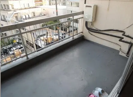 市街地を望むマンションの広々としたベランダ、手すりと外部エアコンユニットがある都会的な居住空間