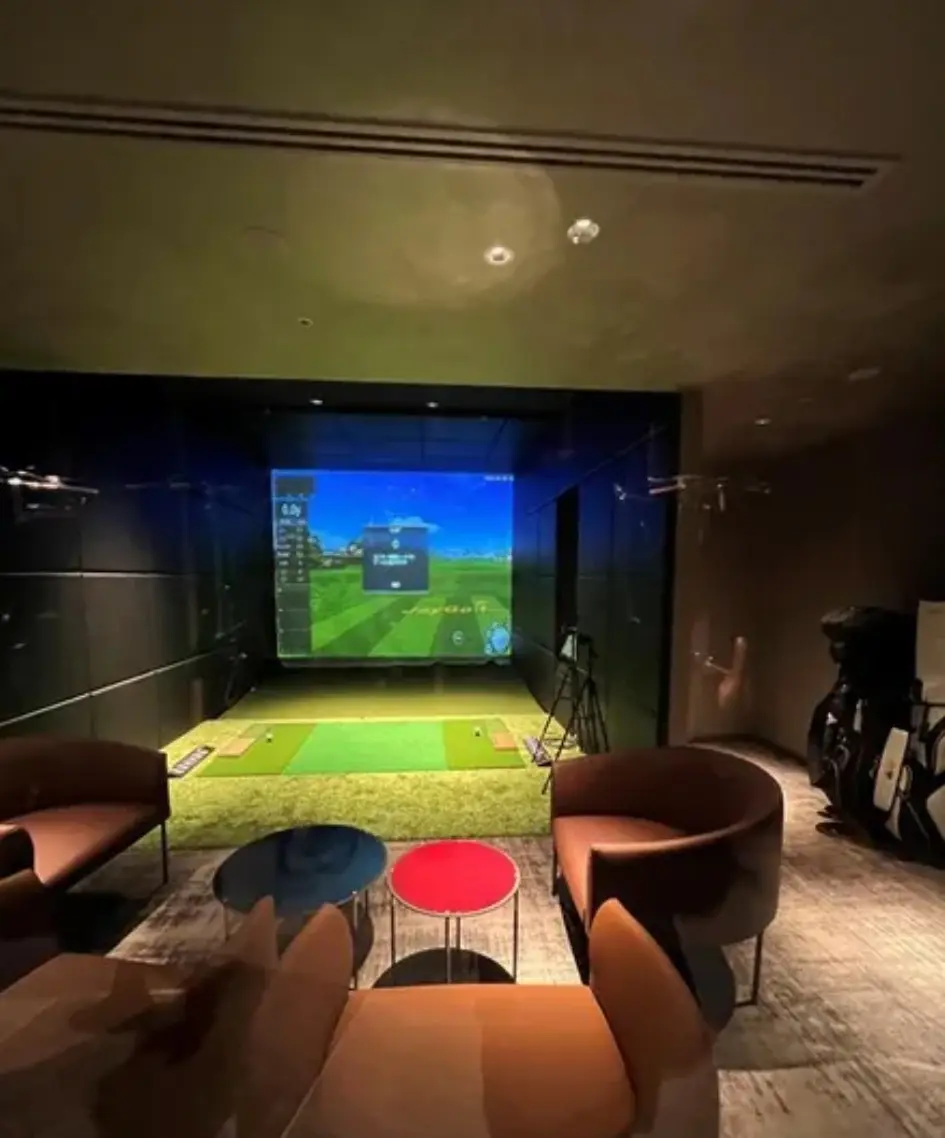 室内ゴルフシミュレーター設備と快適なシート、現代的なインテリアのある部屋
