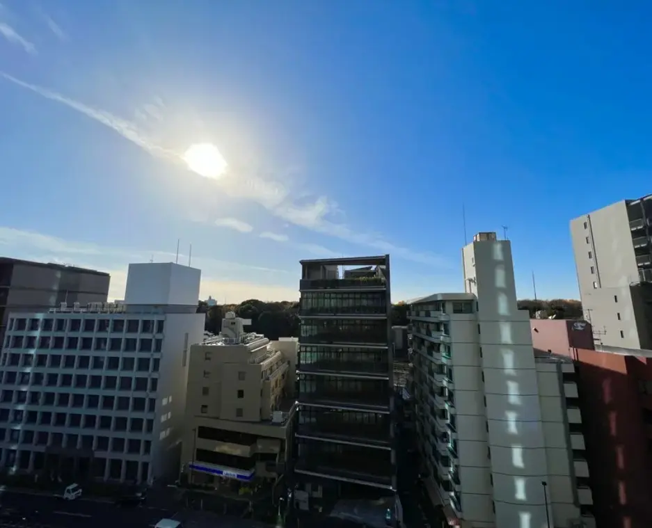 晴れた空と太陽、都市のビル群が映る景色