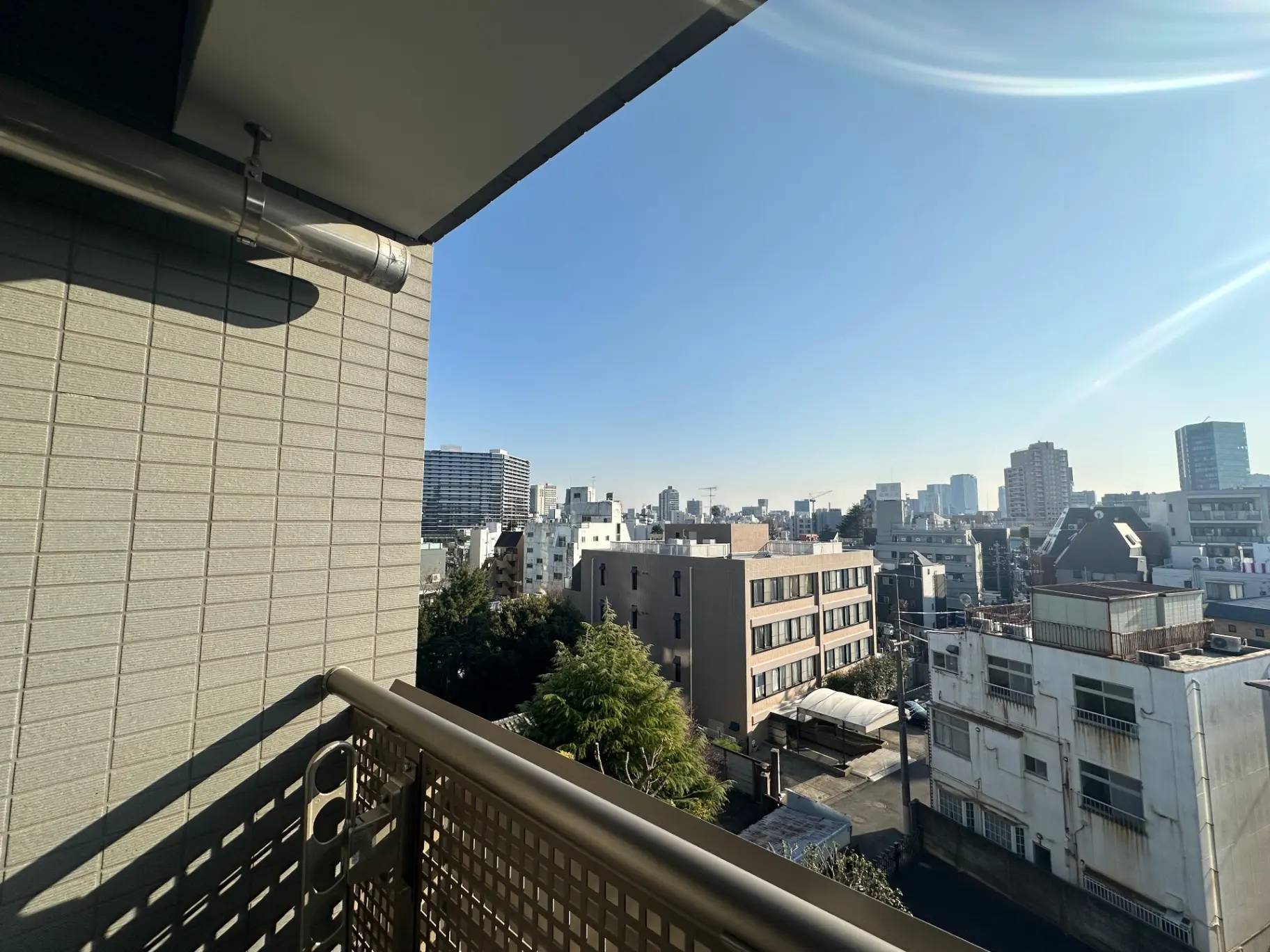 都会の景観が見渡せるバルコニー、青空と建物のシルエットが美しい景色
