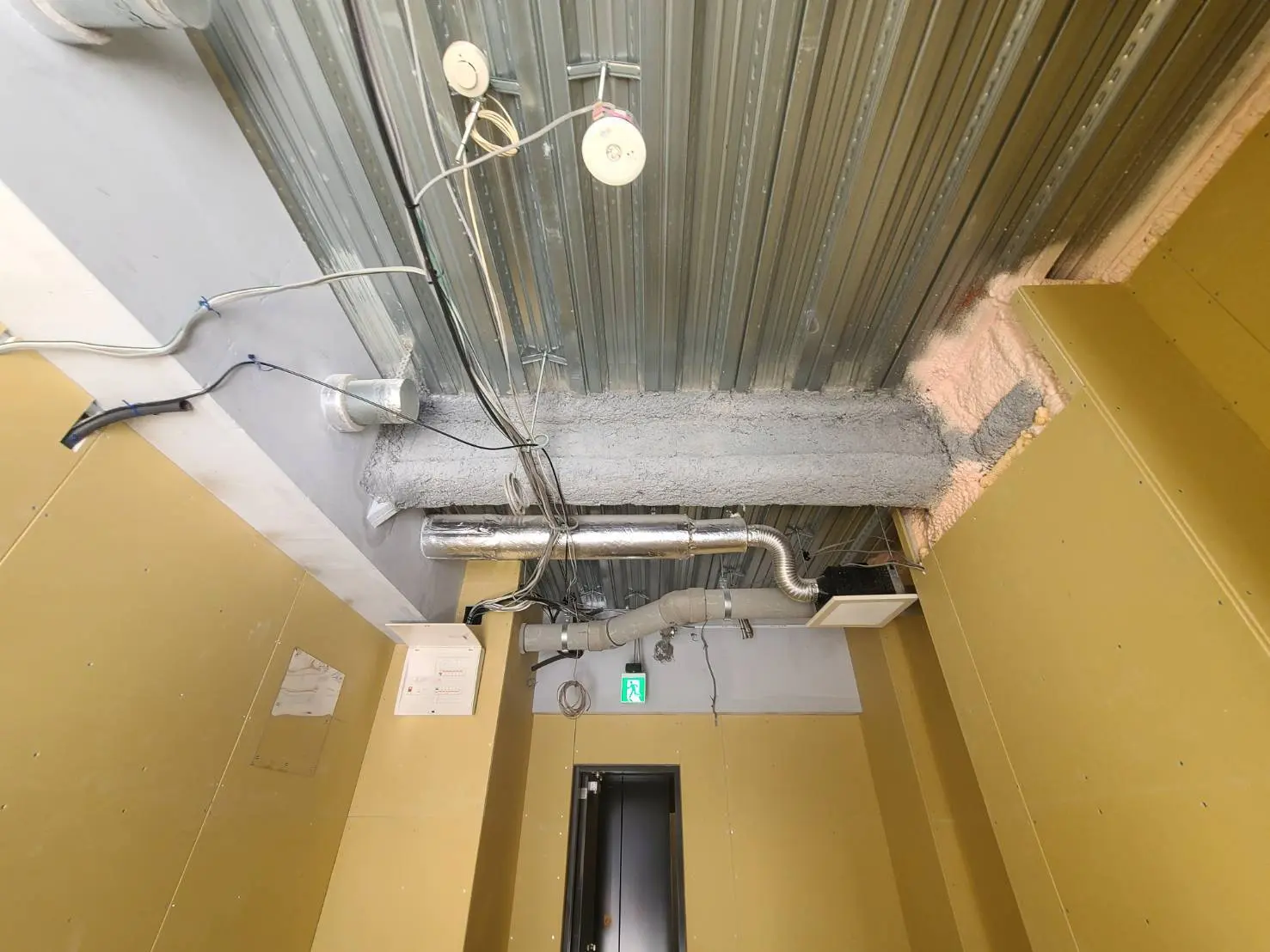 工事中のオフィス天井、露出した配管とダクト、工事用電気配線、改装前のインフラストラクチャー