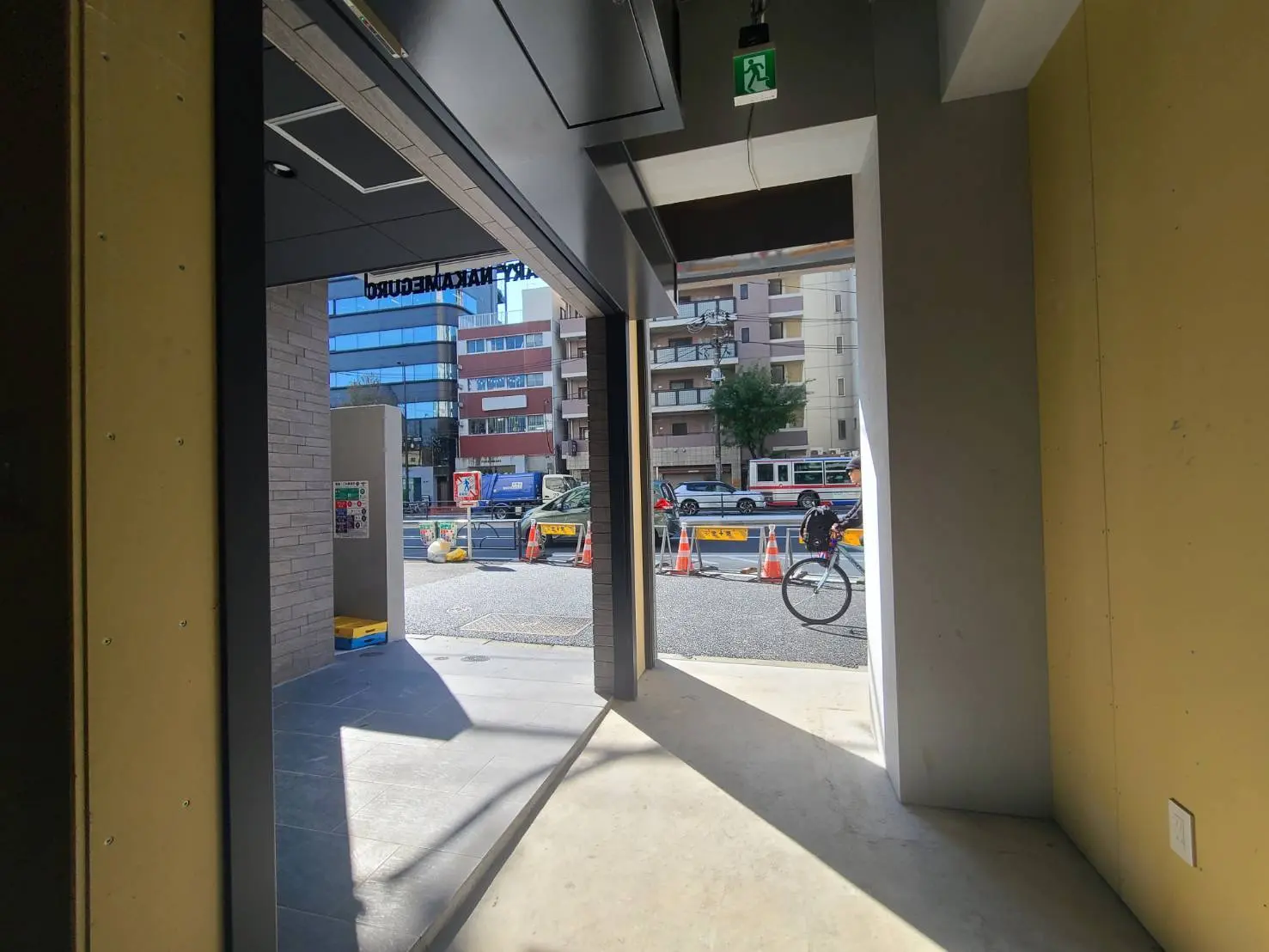 建物の出入り口から見える都市の風景、晴れた日の青空と自転車通行中の人々