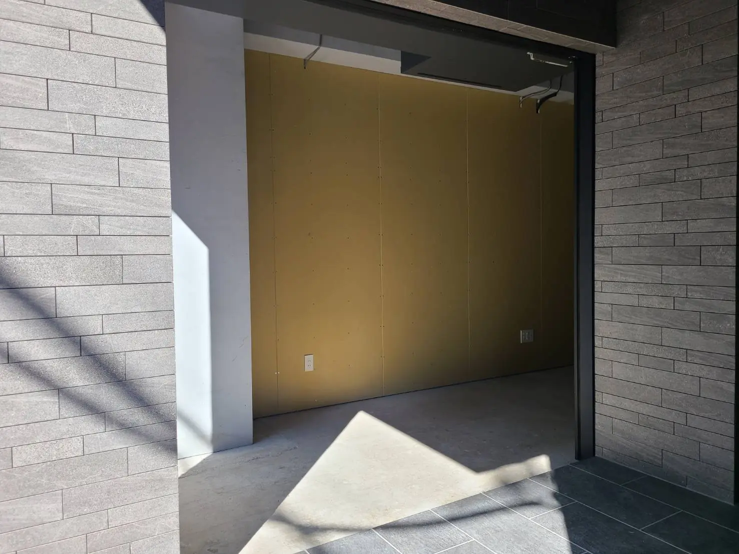 現代的な建築スタイルの屋外ガレージの開口部、午後の日差しと影が落ちるシーン