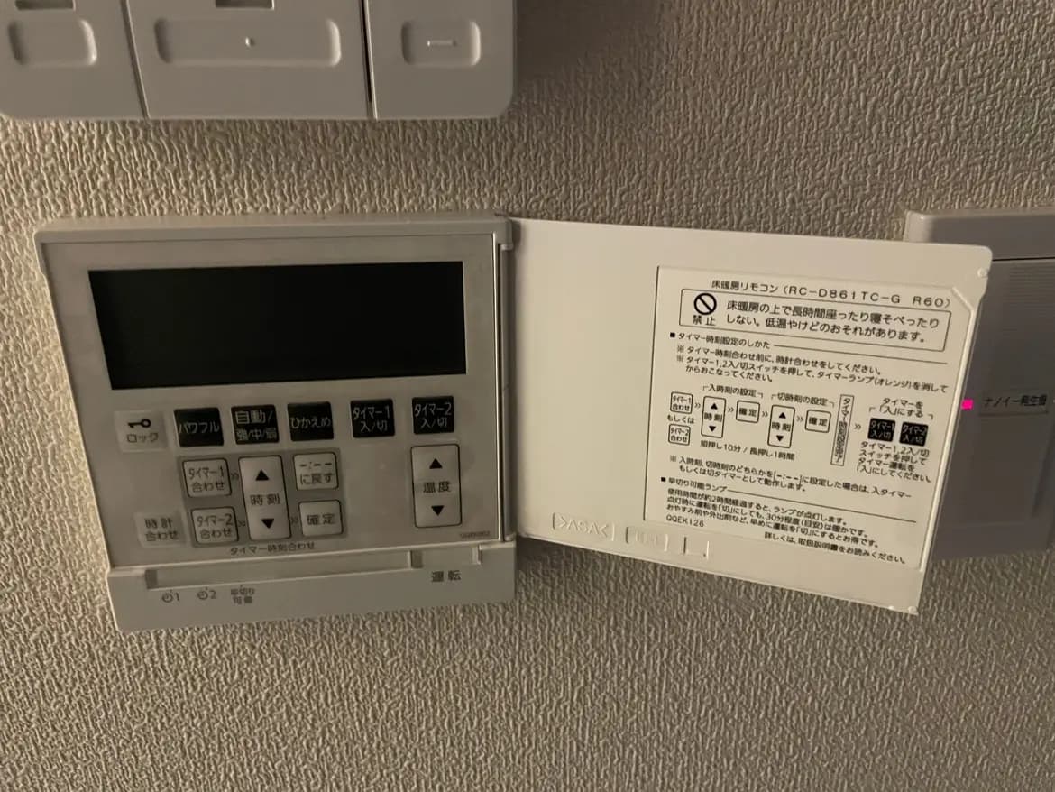家庭用エアコンのリモコンと操作マニュアル、壁に取り付けられた設備のクローズアップ