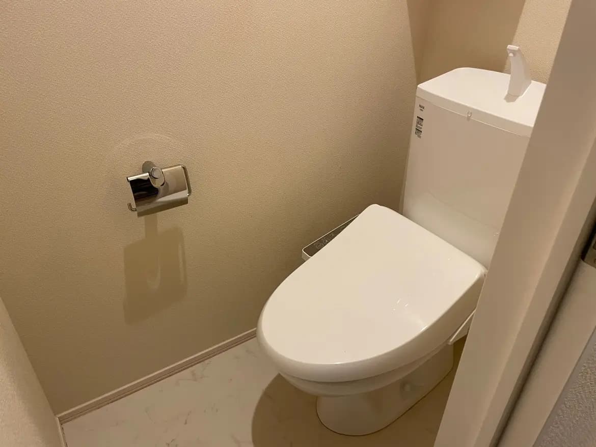 清潔でシンプルなデザインのトイレルーム、壁掛け式トイレットペーパーホルダー、ベージュの壁