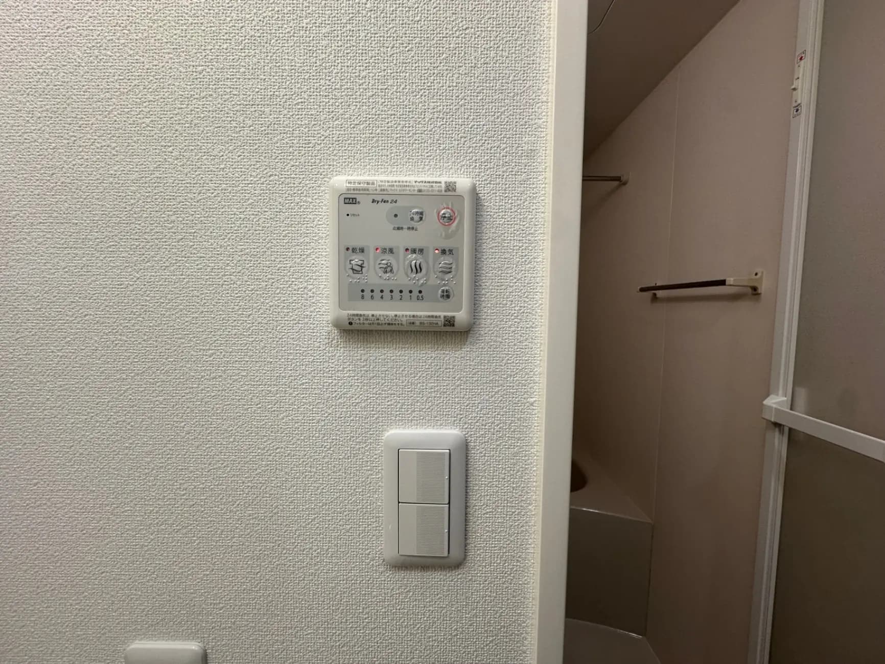 家庭用防犯システムのコントロールパネルと隣接するクローゼットの扉、白い壁とスイッチの詳細写真