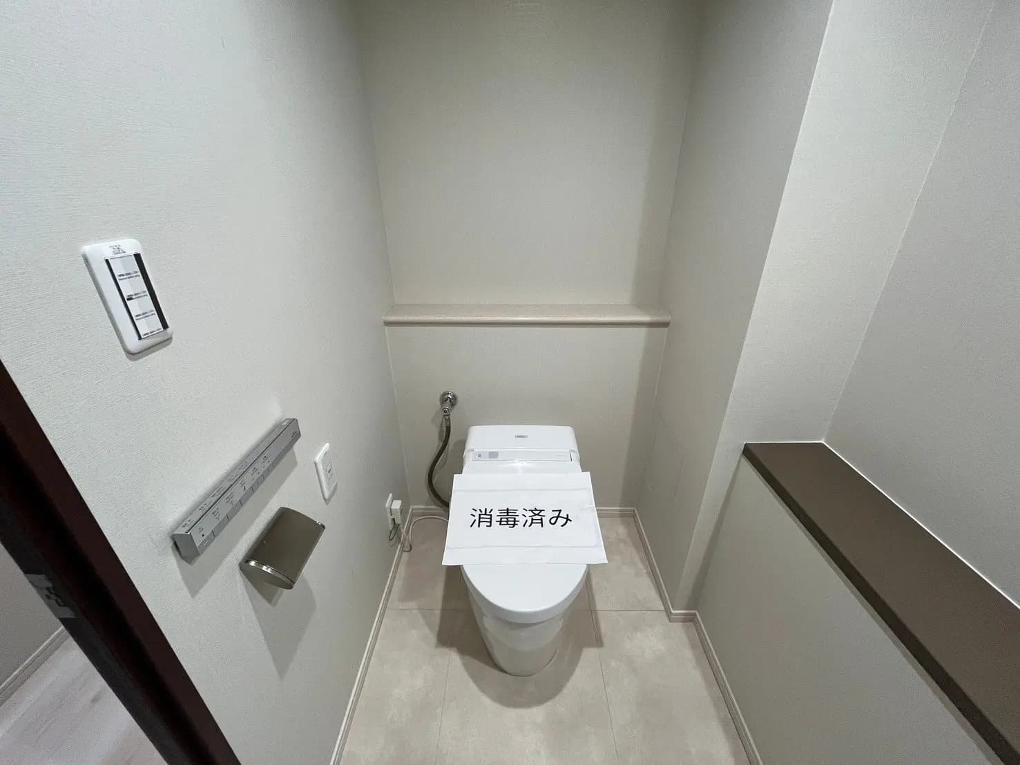 清潔感のあるシンプルなトイレのインテリア、壁に取り付けられた温度調節パネルとトイレットペーパーホルダー