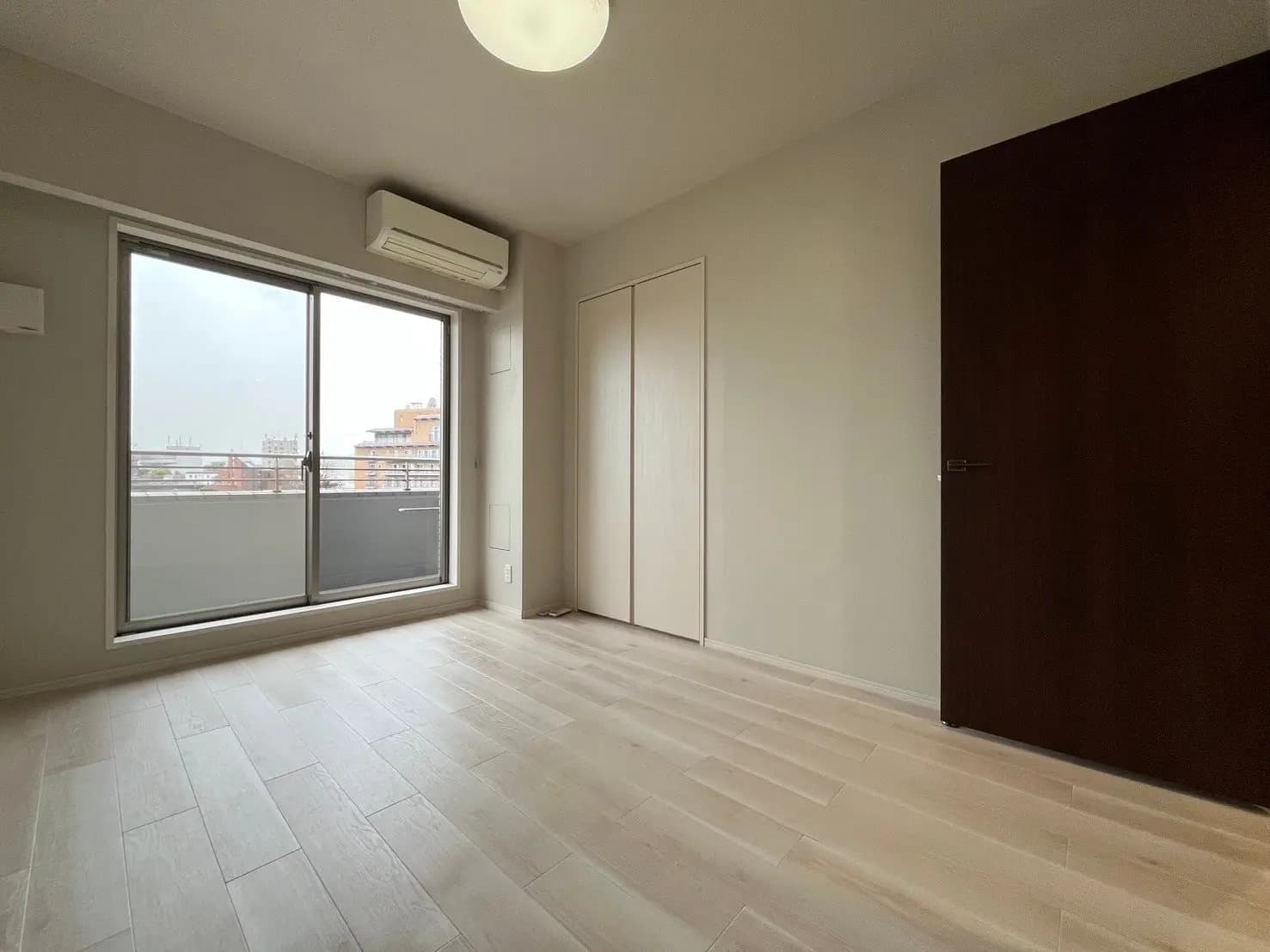 シンプルで洗練された空の部屋、ライトウッドのフローリング、大きな窓からの自然光、モダンな建築スタイル