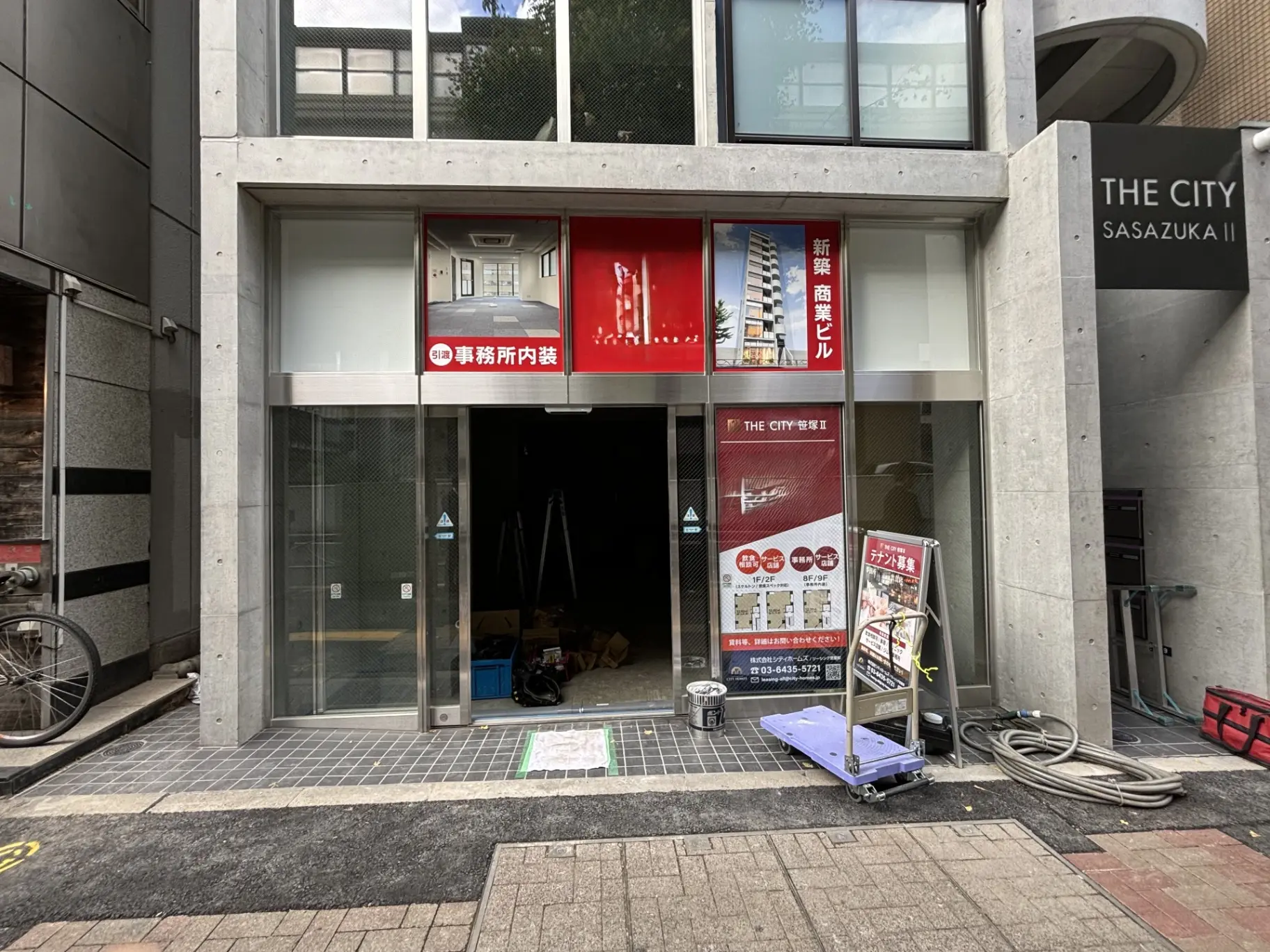 建設中の商業ビルの外観、THE CITY SASAZUKA IIの看板があるファサード、歩道と自転車