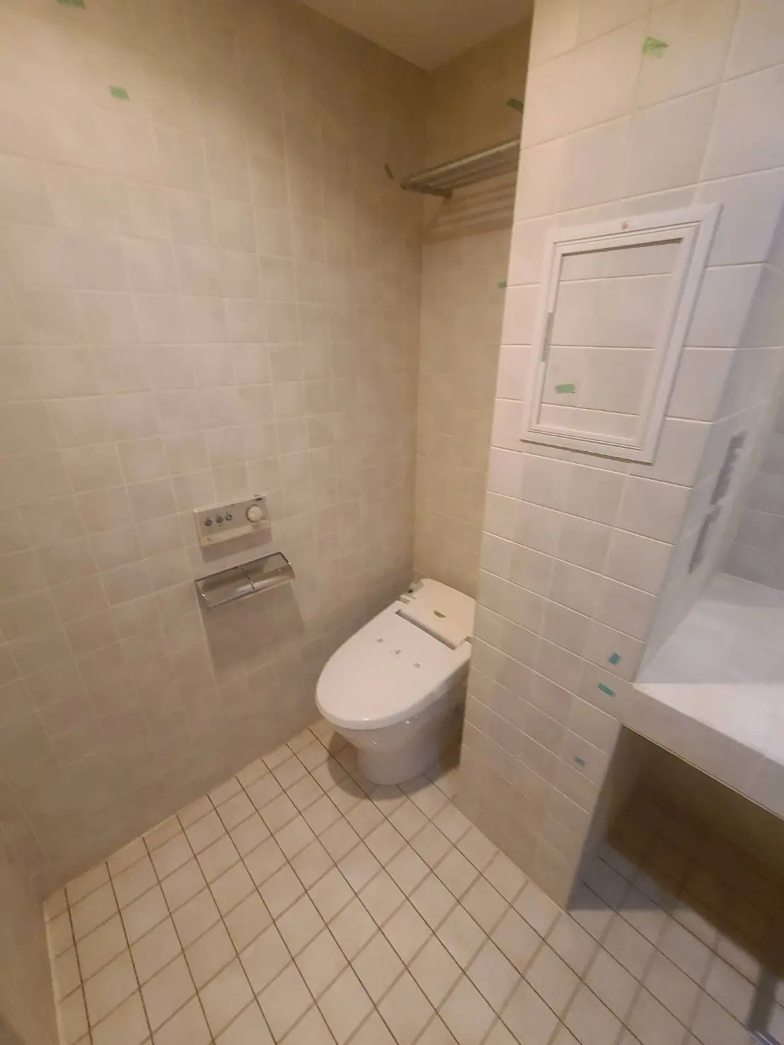シンプルなデザインのトイレとシャワーのあるバスルーム、タイル張りの壁と床