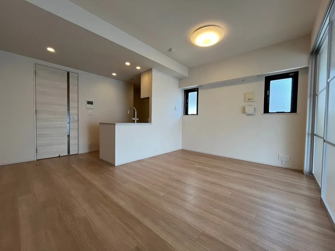 新築マンションの広々としたリビングダイニング、木目調フロアと白い壁、モダンなインテリアデザイン
