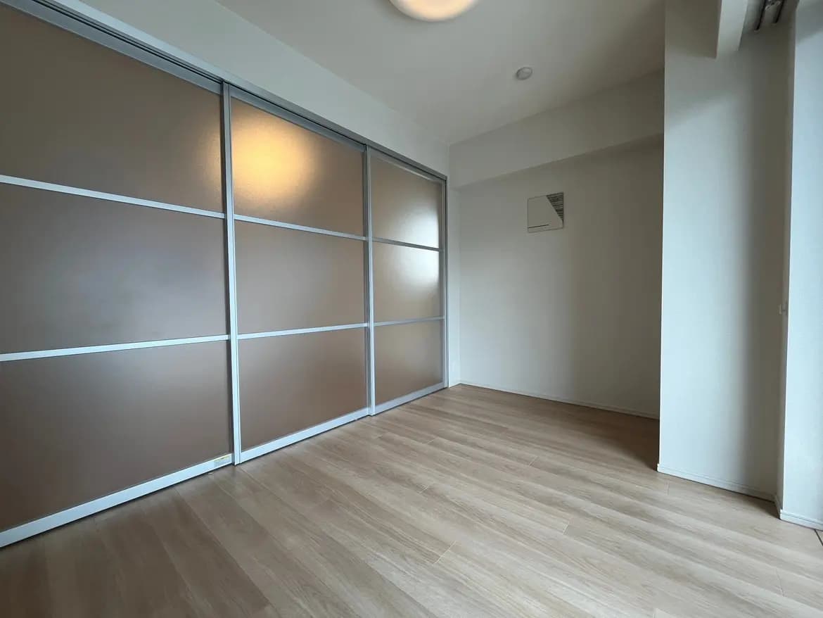 シンプルでモダンな空間、木目調フローリングと大きなクローゼット、柔らかい照明が特徴の空の部屋