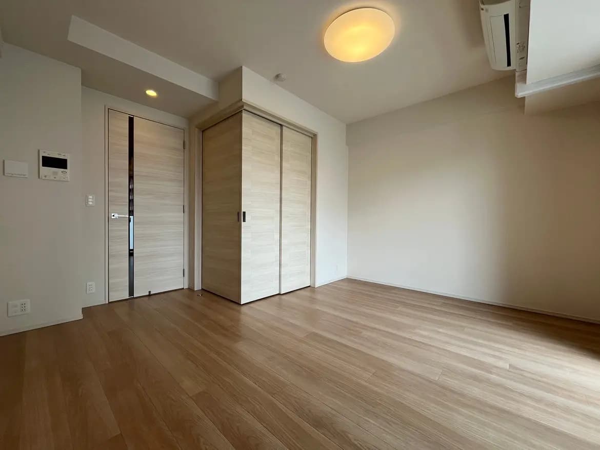 シンプルで洗練されたデザインの空の部屋、木目調のフローリング、白い壁、モダンな照明設備