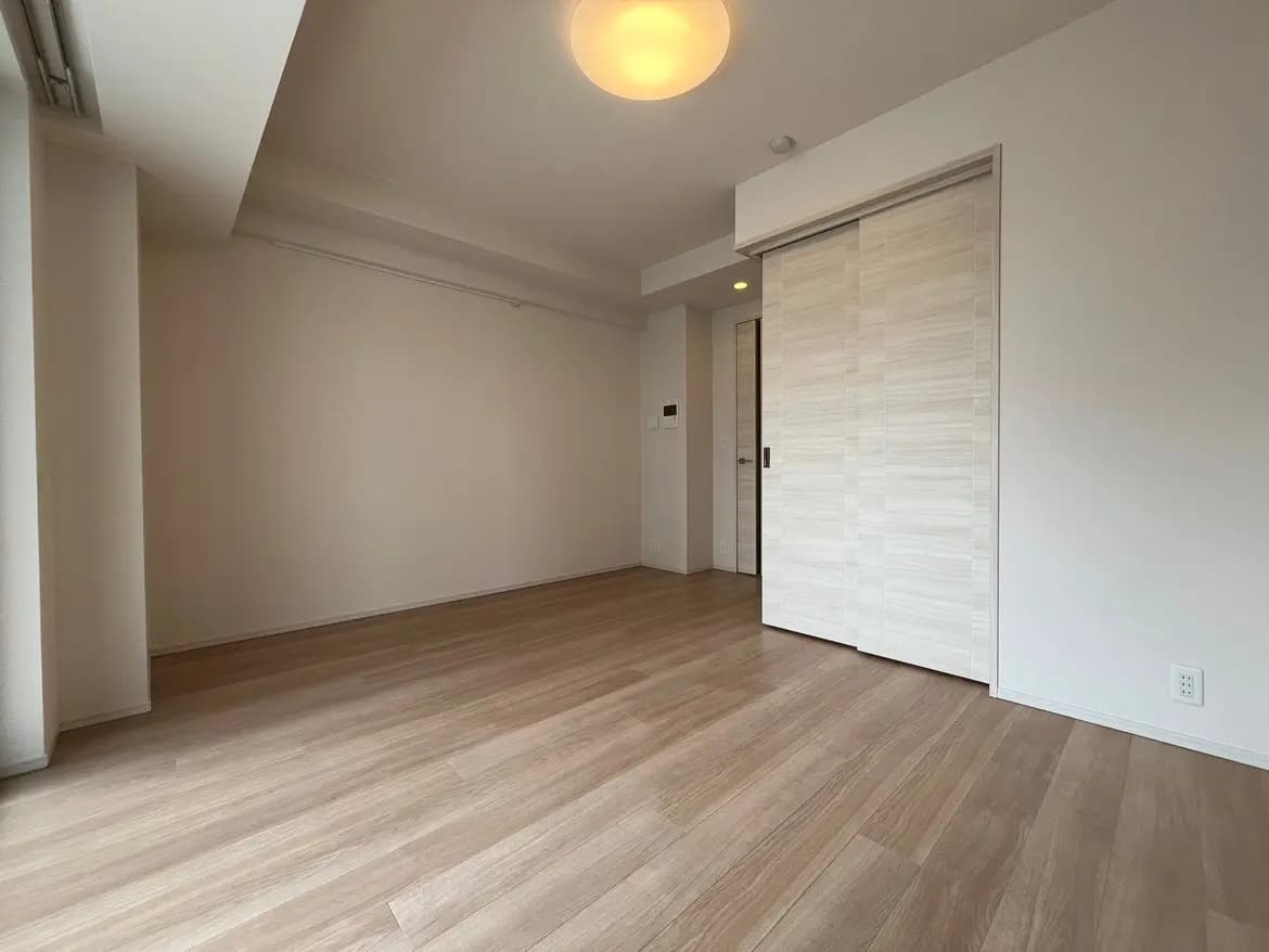 シンプルでモダンなデザインの空の部屋、木目調のフローリングと白い壁、天井のライト