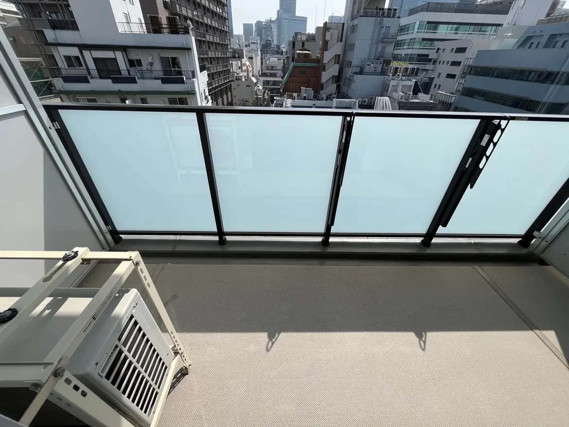 都会の景色を楽しめるモダンなマンションのバルコニー、透明なガラスの手すりとタイルフローリング