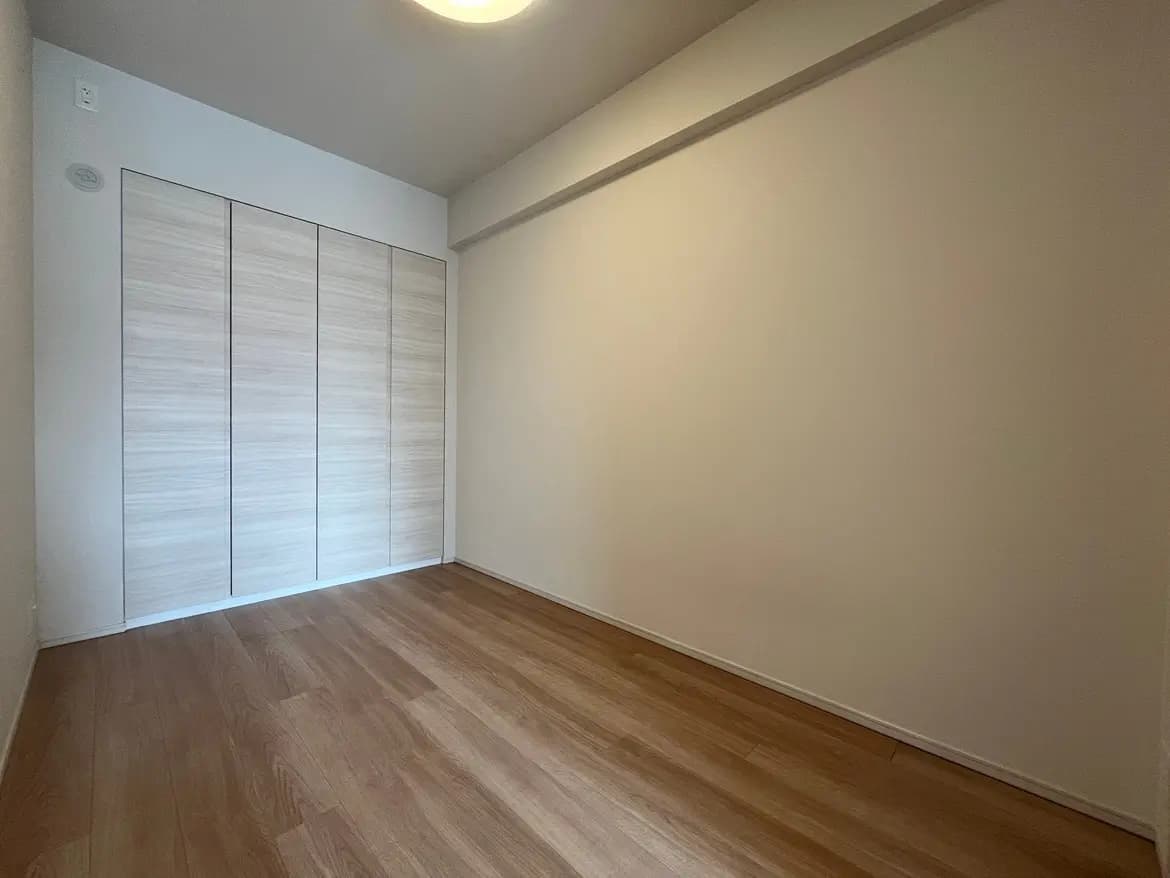 シンプルなデザインの空の部屋、木目調のフロアと大型のクローゼット、シーリングライト付き