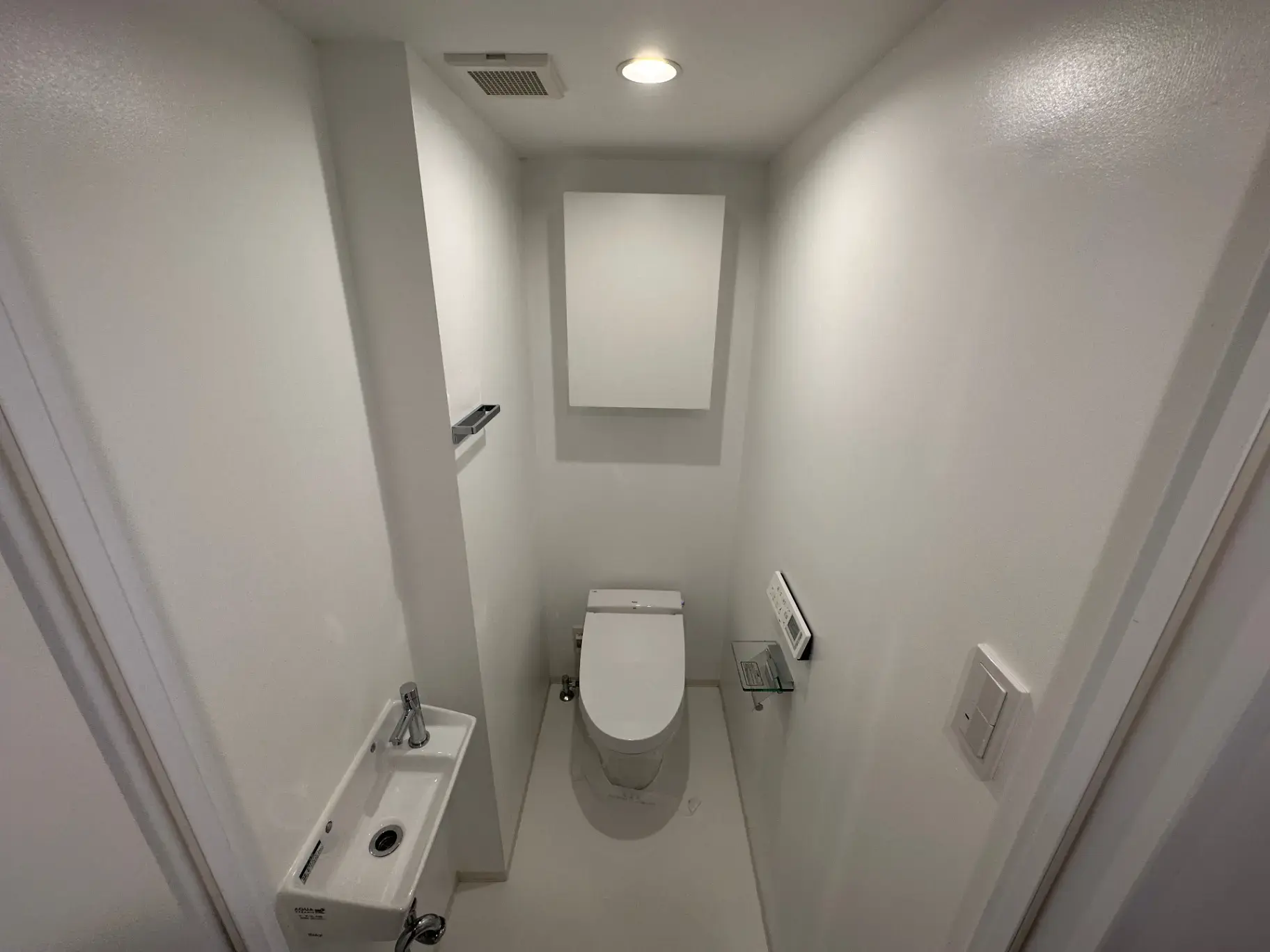 シンプルなデザインのトイレと手洗い器、白い壁と清潔感あふれるインテリア