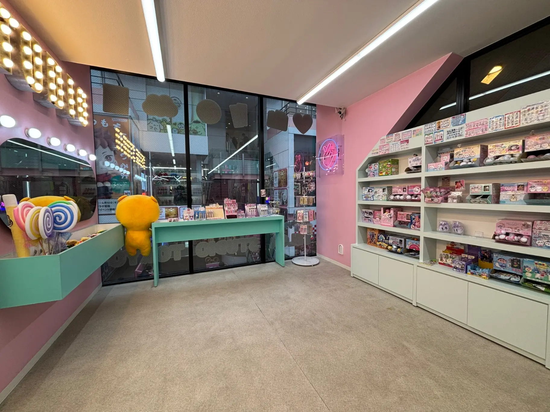 - 明るいピンクの壁と緑のテーブル、カラフルなお菓子や雑貨が並ぶかわいいショップの店内風景、ポップなインテリアデザイン