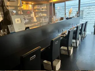 - モダンなカウンター席が並ぶ飲食店の内部、黒を基調としたインテリアと明るい照明の雰囲気