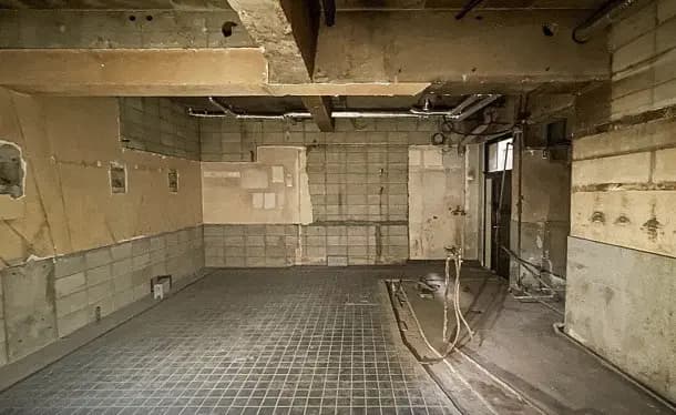 - 工事中の空間、剥がれた壁紙とコンクリートの壁、広い床面と露出した配管が特徴的なインテリア