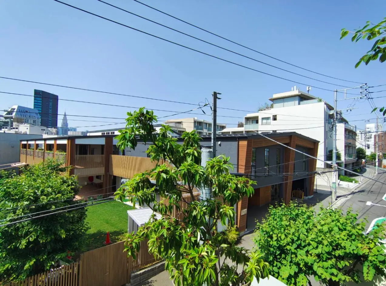 - 緑豊かな都市の風景、現代的な建物と青空、電線が交差する街並みの一角の写真