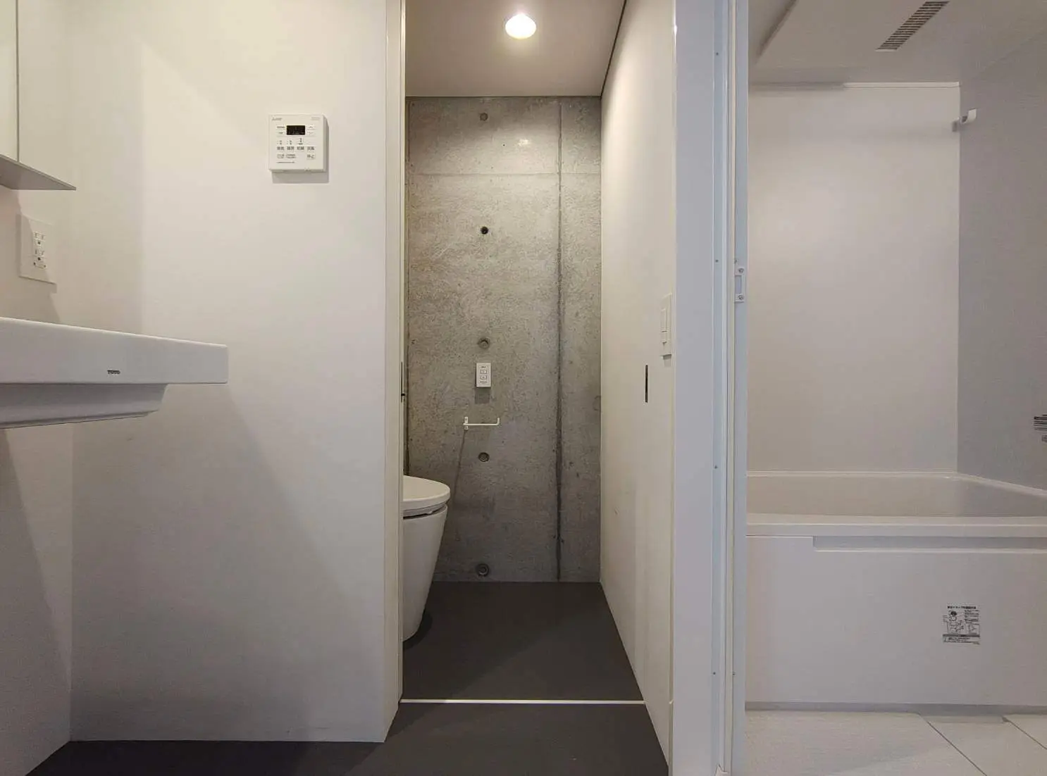 - シンプルでモダンなデザインのバスルーム、コンクリートの壁、トイレと洗面所が配置された空間