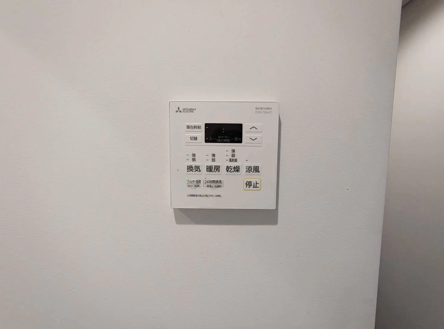 - 壁に取り付けられた三菱電機の空調コントロールパネル、温度設定やモード切替ボタンがあるデザイン