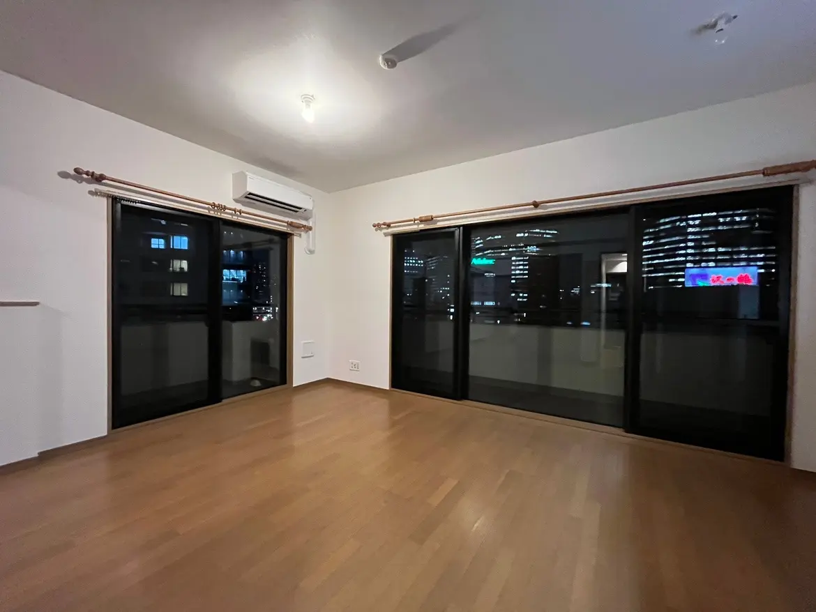 - 夜景が楽しめる明るいリビングルーム、広々とした木製フローリング、黒い大きな窓からの眺め